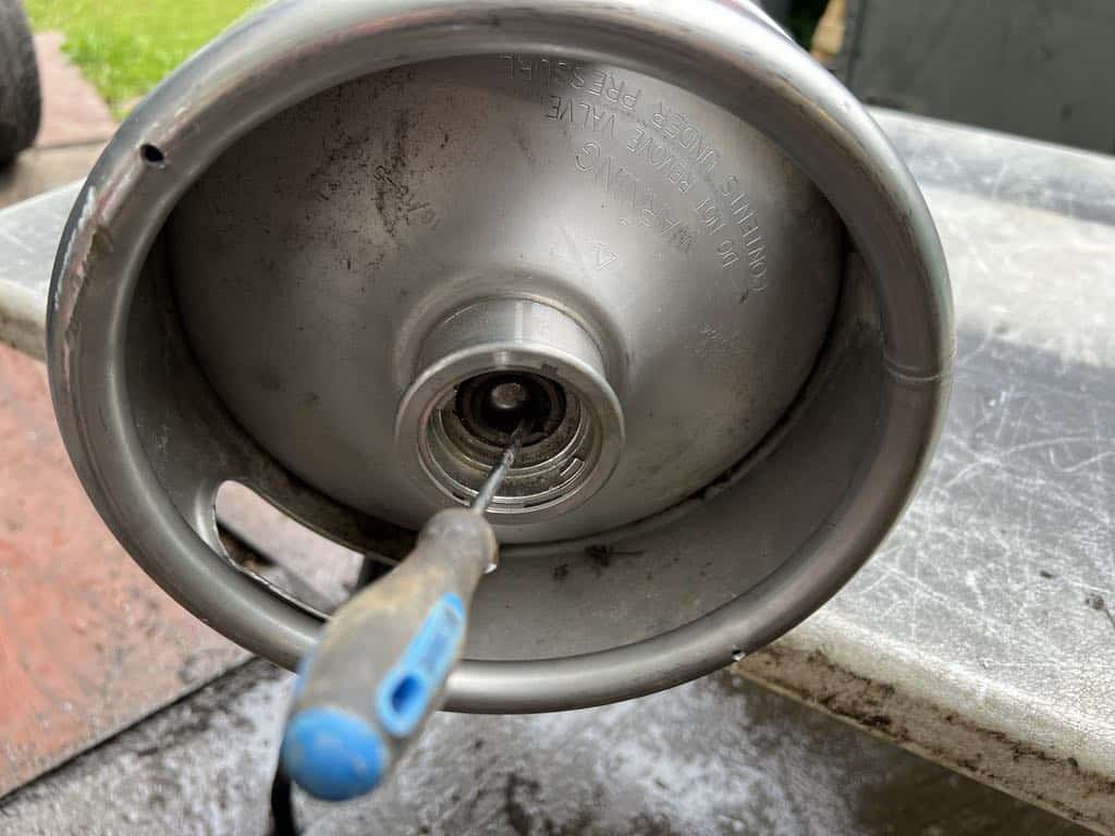 Degassing a keg with a screw driver.