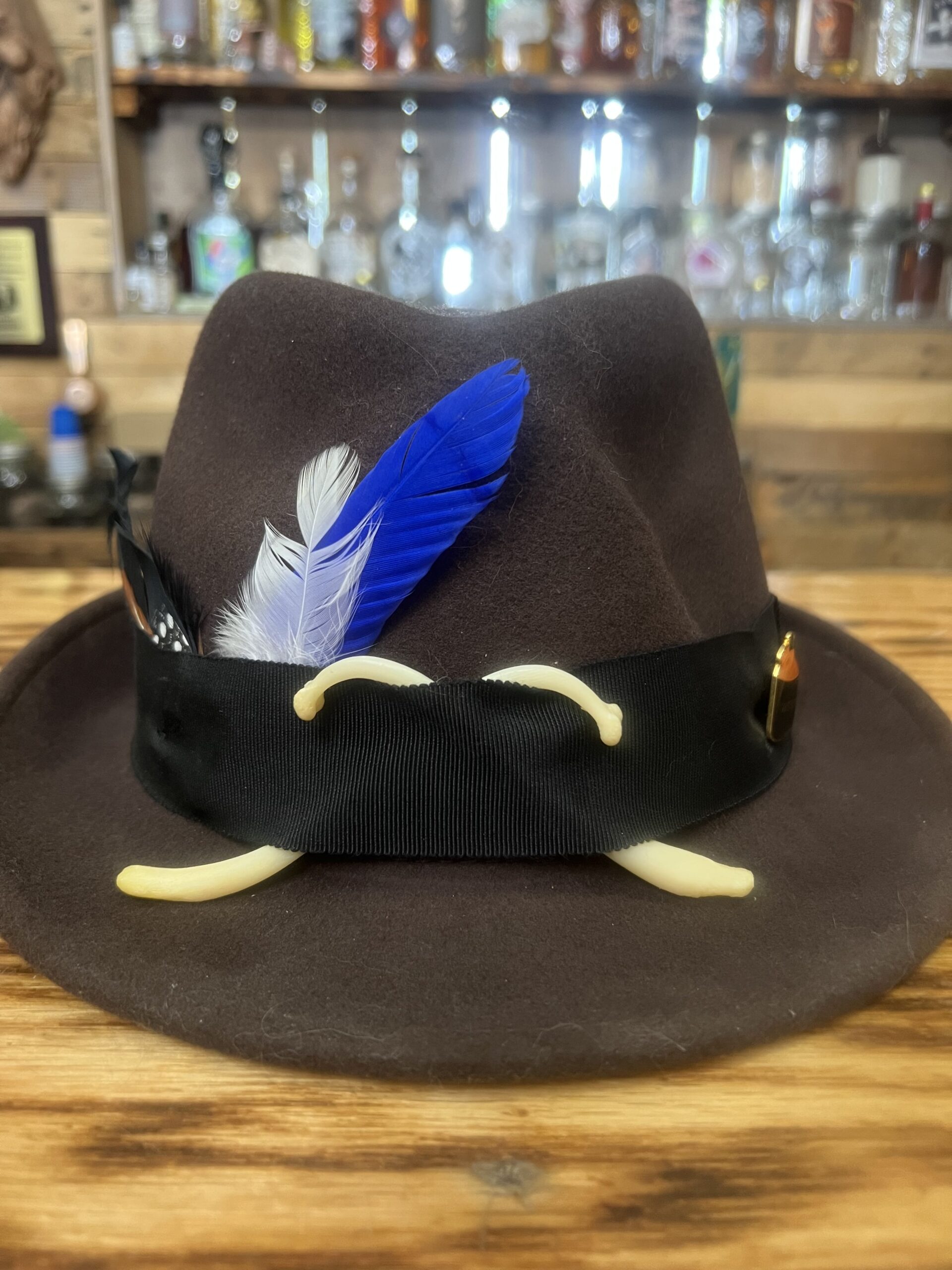 Rustic Popcorn style moonshiner hat with genuine raccoon baculum, black ribbon band, and natural feather arrangement.